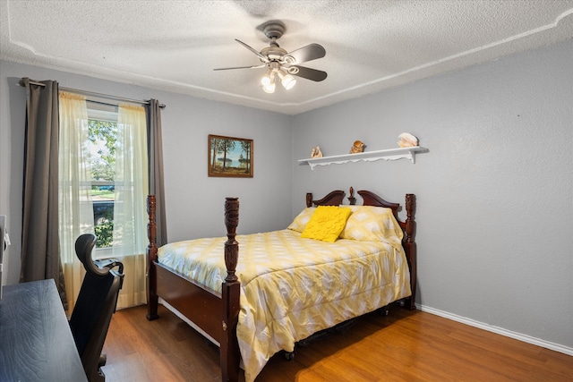 bedroom featuring ceiling fan, hardwood / wood-style floors, and a textured ceiling