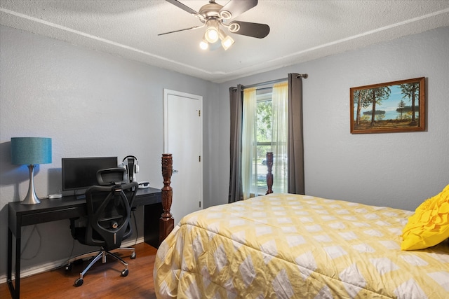 bedroom with ceiling fan, hardwood / wood-style flooring, and a textured ceiling