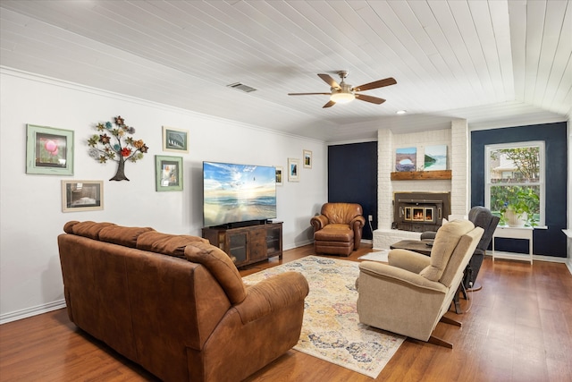 living room featuring ceiling fan, ornamental molding, dark wood-type flooring, wooden ceiling, and a fireplace