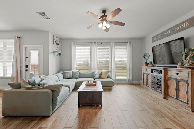 living room featuring ceiling fan, plenty of natural light, and light hardwood / wood-style floors