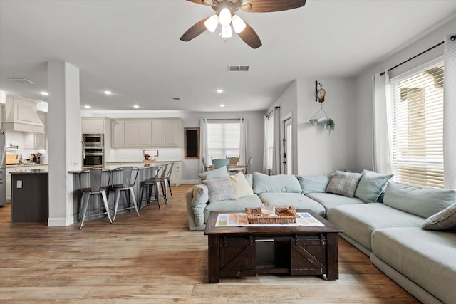 living room with light hardwood / wood-style floors and ceiling fan