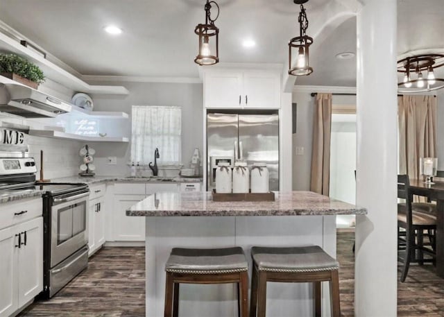 kitchen with white cabinets, a kitchen island, stainless steel appliances, and decorative light fixtures