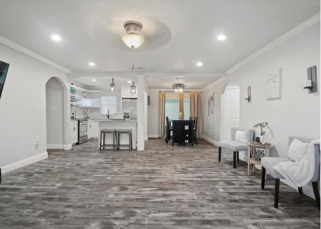 living room featuring ceiling fan with notable chandelier, crown molding, and dark wood-type flooring