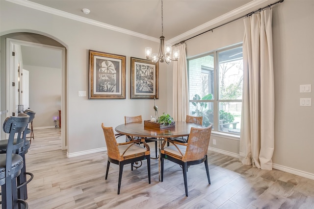 dining space featuring light wood-type flooring, ornamental molding, and a chandelier