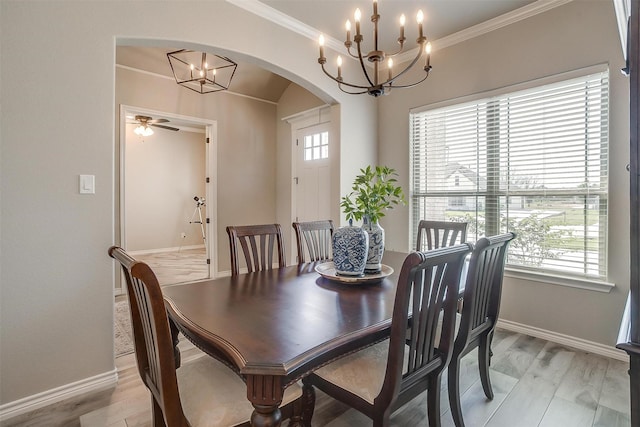 dining space with a chandelier, baseboards, arched walkways, and crown molding
