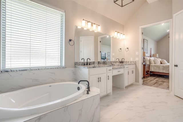 bathroom featuring vanity, a relaxing tiled tub, and lofted ceiling