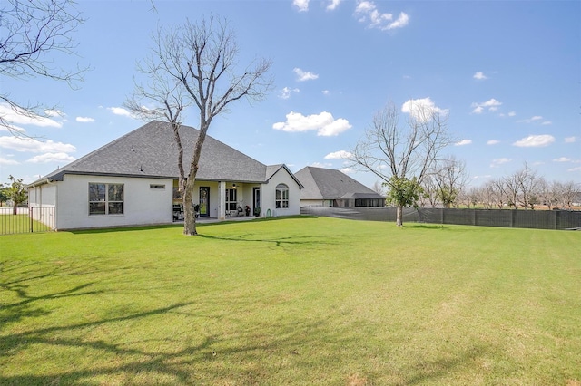 rear view of house with a fenced backyard and a lawn