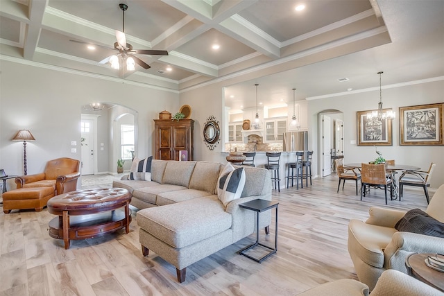 living room featuring ceiling fan with notable chandelier, coffered ceiling, ornamental molding, and light hardwood / wood-style flooring