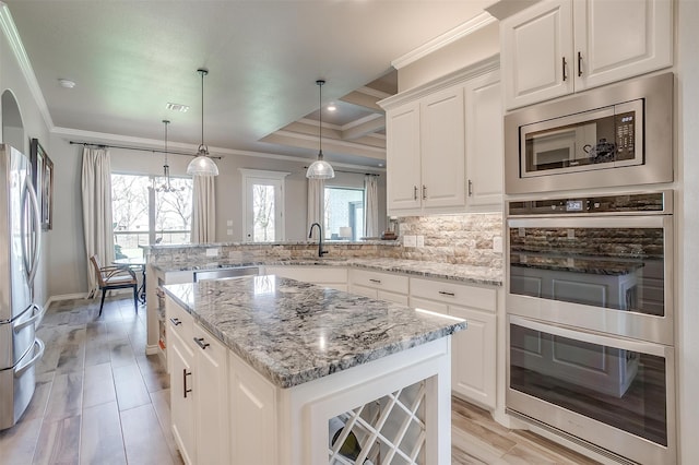 kitchen featuring white cabinets, kitchen peninsula, decorative light fixtures, appliances with stainless steel finishes, and a center island