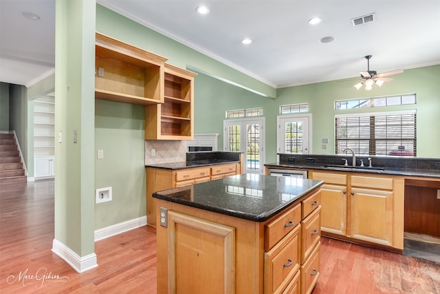 kitchen featuring sink, a kitchen island, light hardwood / wood-style flooring, decorative backsplash, and crown molding