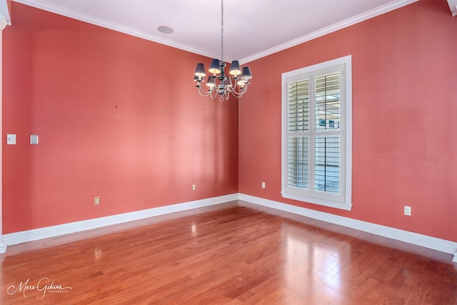 empty room featuring crown molding, an inviting chandelier, and hardwood / wood-style flooring