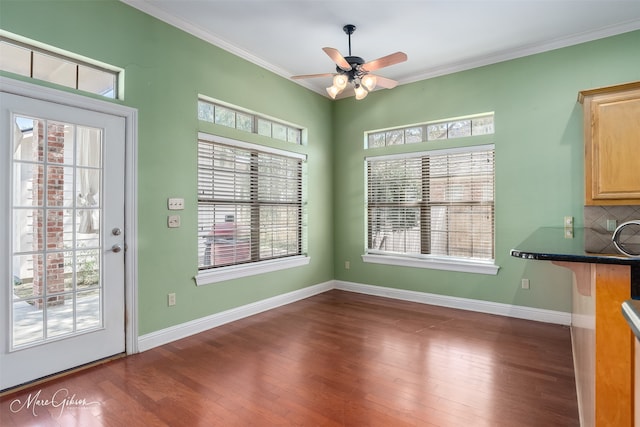 unfurnished dining area featuring crown molding, dark wood-type flooring, and a healthy amount of sunlight