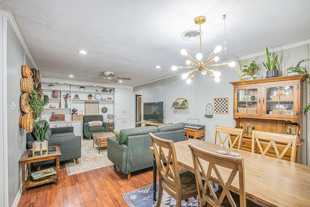 dining area with a textured ceiling, crown molding, ceiling fan with notable chandelier, and hardwood / wood-style flooring