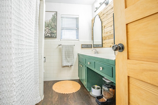 bathroom with walk in shower, wood-type flooring, vanity, and tile walls