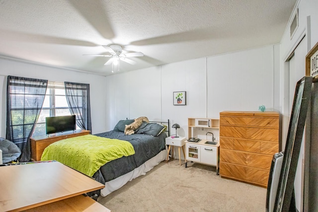 bedroom with a closet, a textured ceiling, light colored carpet, and ceiling fan