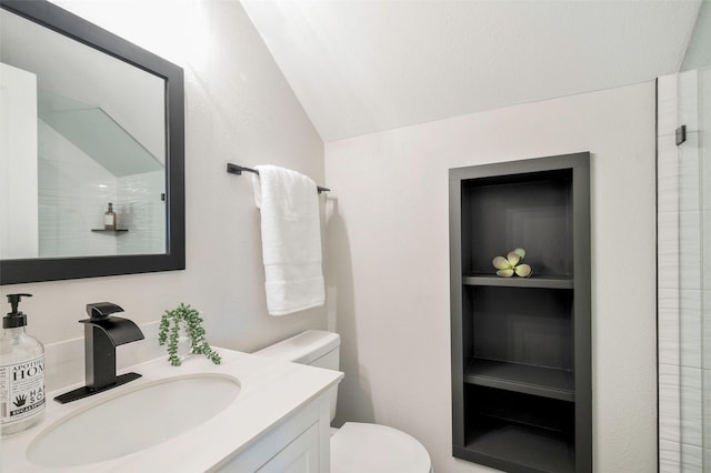 bathroom featuring a shower, vanity, toilet, and lofted ceiling