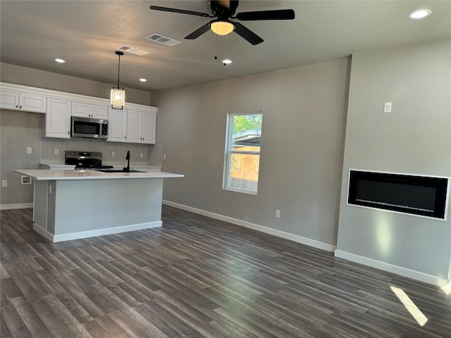 kitchen featuring dark hardwood / wood-style flooring, stainless steel appliances, hanging light fixtures, an island with sink, and white cabinetry