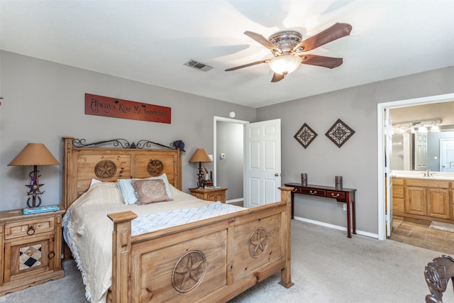 bedroom with ceiling fan, sink, ensuite bath, and light carpet