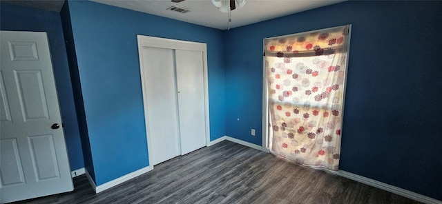 unfurnished bedroom featuring a closet, dark wood-style flooring, baseboards, and visible vents