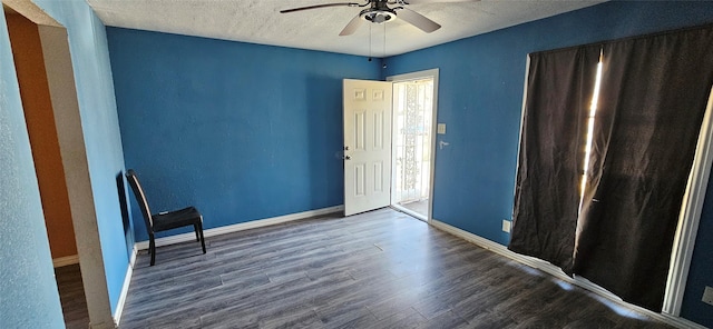 empty room featuring ceiling fan, dark wood-type flooring, and a textured ceiling