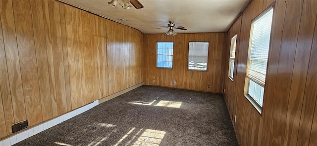 carpeted empty room with ornamental molding, ceiling fan, and wooden walls