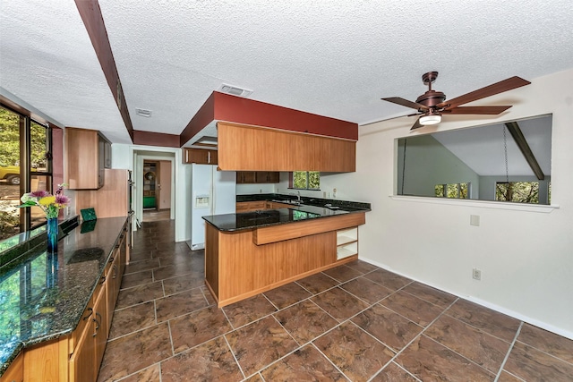 kitchen featuring white refrigerator with ice dispenser, sink, ceiling fan, a textured ceiling, and kitchen peninsula