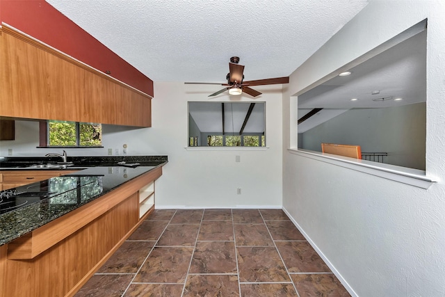 kitchen featuring ceiling fan, sink, dark stone counters, a textured ceiling, and black stovetop