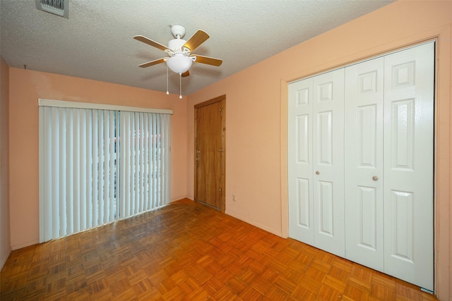 unfurnished bedroom featuring parquet floors, a textured ceiling, and ceiling fan