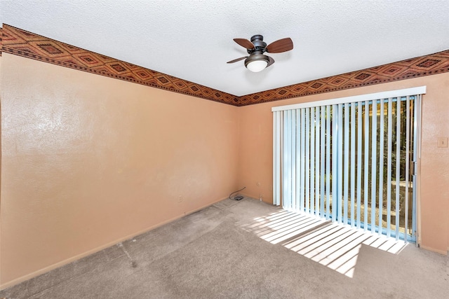 carpeted empty room with ceiling fan and a textured ceiling