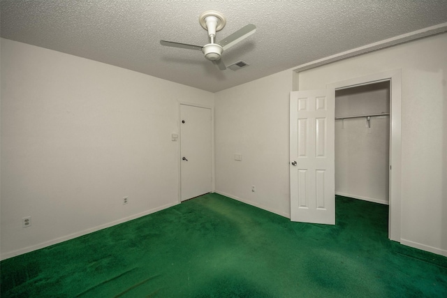 unfurnished bedroom with ceiling fan, dark carpet, a textured ceiling, and a closet