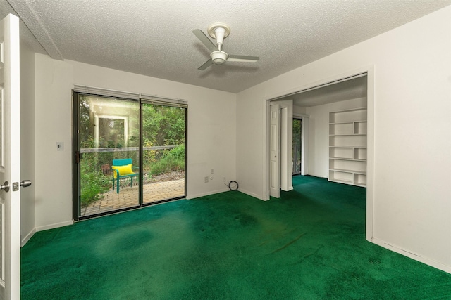 unfurnished room with ceiling fan, dark carpet, built in features, and a textured ceiling