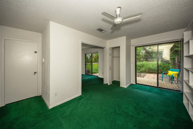 unfurnished room featuring a textured ceiling, dark carpet, ceiling fan, and a healthy amount of sunlight