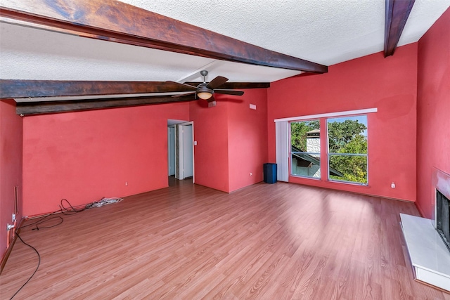 unfurnished living room with beamed ceiling, ceiling fan, a textured ceiling, and hardwood / wood-style floors