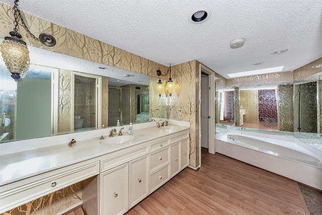 full bathroom with a textured ceiling, toilet, vanity, shower with separate bathtub, and hardwood / wood-style flooring