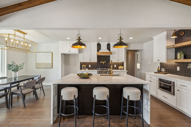 kitchen with custom exhaust hood, light stone countertops, hanging light fixtures, and stainless steel oven