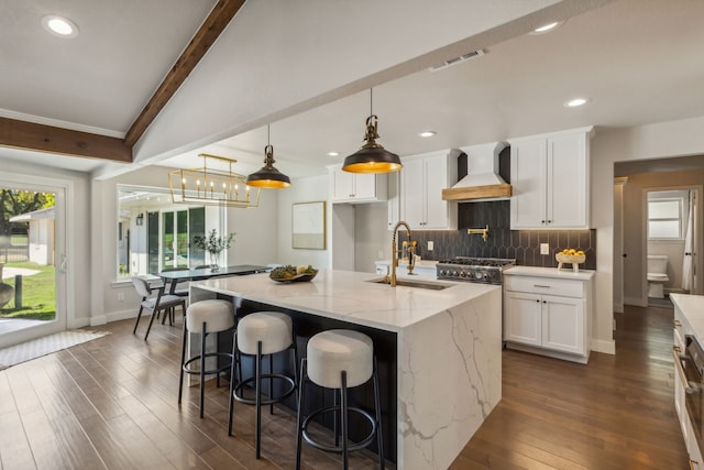 kitchen with white cabinetry, a kitchen island with sink, and sink