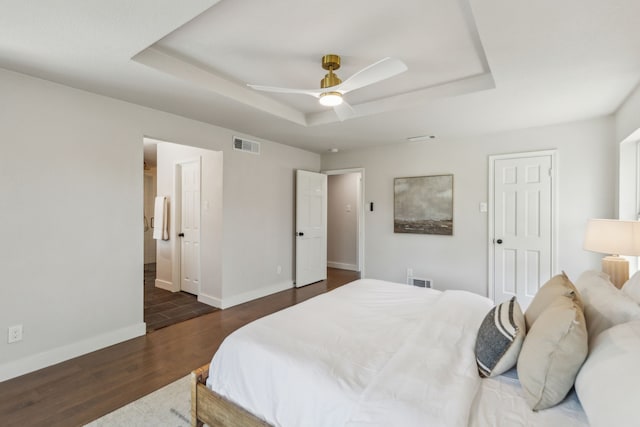 bedroom with a tray ceiling, dark hardwood / wood-style flooring, and ceiling fan