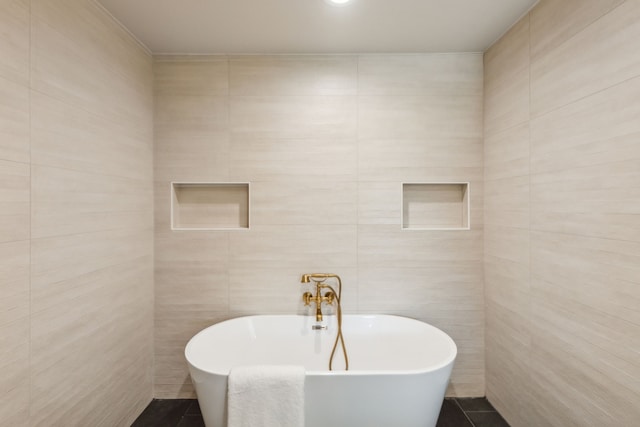 bathroom with tile walls, a bath, and tile patterned floors