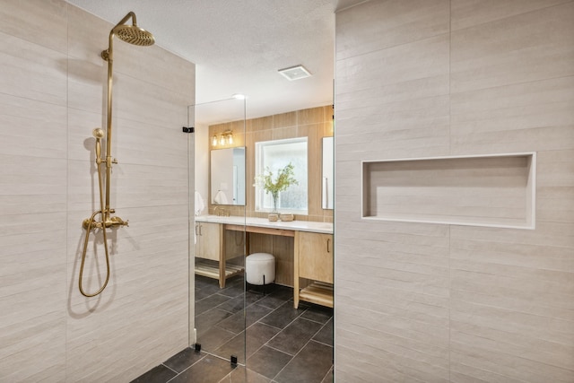 bathroom with walk in shower, vanity, a textured ceiling, and tile patterned floors