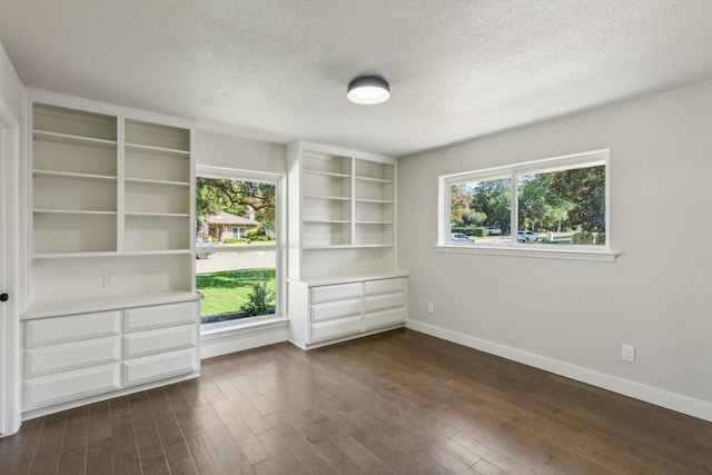 interior space with a textured ceiling, dark hardwood / wood-style flooring, and multiple windows