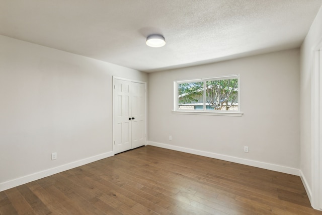 unfurnished room with a textured ceiling and dark hardwood / wood-style flooring