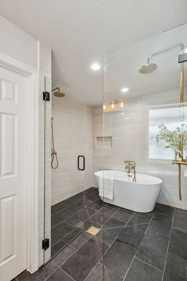 bathroom with a textured ceiling, shower with separate bathtub, tile walls, and tile patterned floors