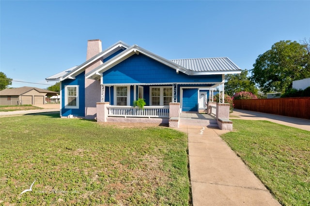 bungalow-style home with a chimney, a porch, fence, and a front lawn