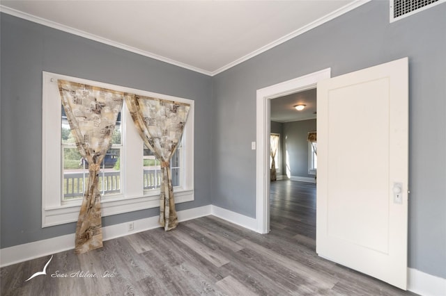 unfurnished room with wood finished floors, a wealth of natural light, ornamental molding, and visible vents