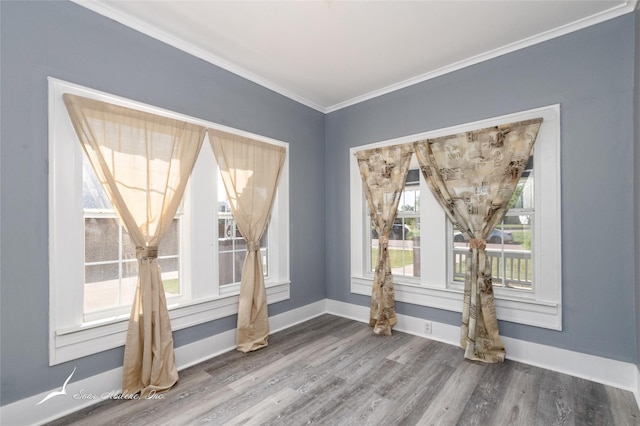 unfurnished dining area with baseboards, ornamental molding, and wood finished floors