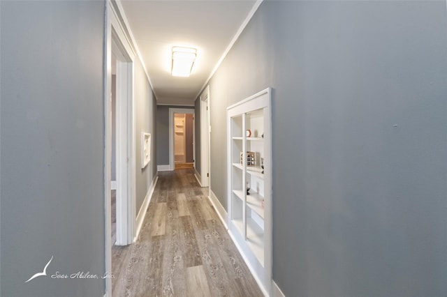 hall with baseboards, wood finished floors, and crown molding