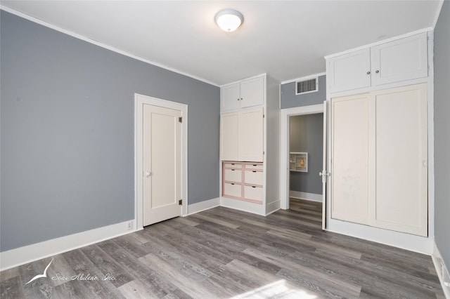 unfurnished bedroom featuring baseboards, ornamental molding, visible vents, and dark wood finished floors
