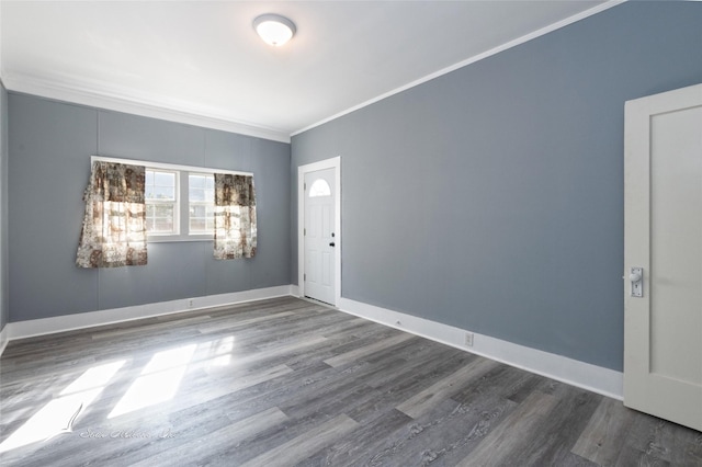 spare room featuring baseboards, crown molding, and wood finished floors