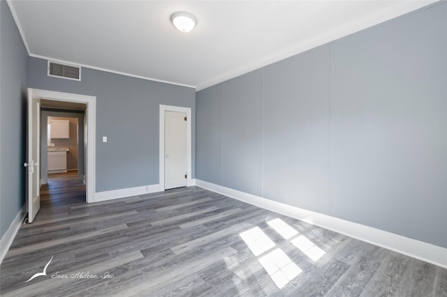unfurnished bedroom with baseboards, visible vents, wood finished floors, and ornamental molding