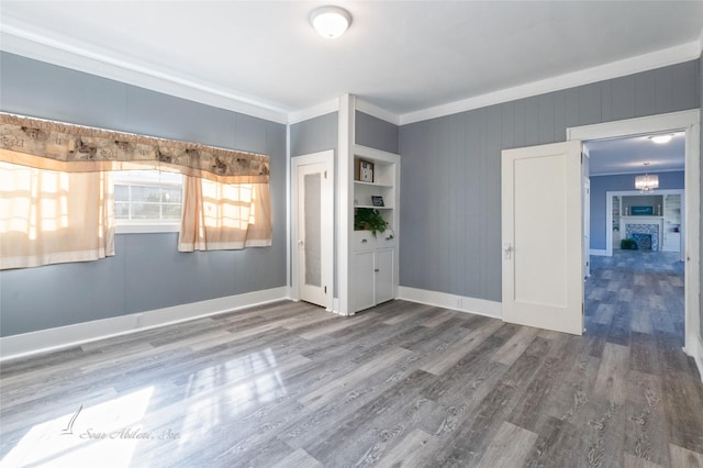 spare room featuring baseboards, wood finished floors, and crown molding